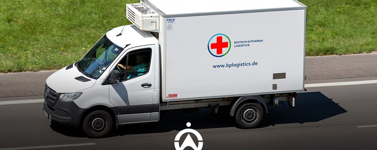 A white refrigerated delivery truck on the road, marked with a red cross and "Biotech & Pharma Logistics" branding.