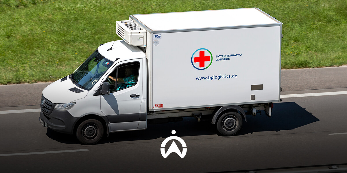 A white refrigerated delivery truck on the road, marked with a red cross and "Biotech & Pharma Logistics" branding.