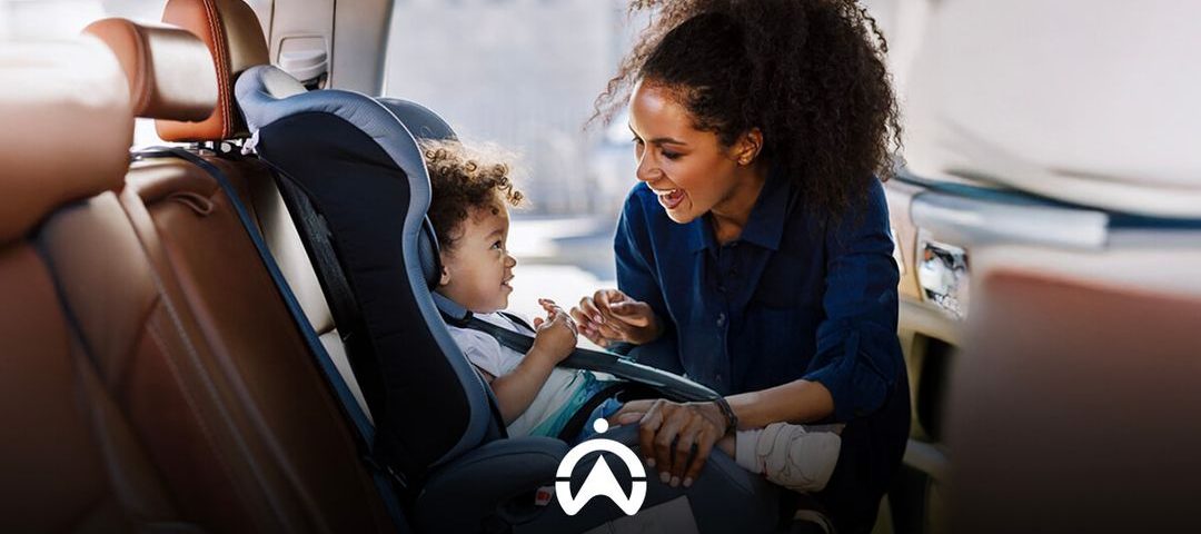 A caregiver interacts with a child in a car seat, showcasing a caring moment in a vehicle's back seat.