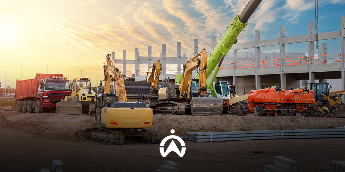 A construction site at sunset featuring various heavy machinery, including excavators and trucks, near a concrete structure.