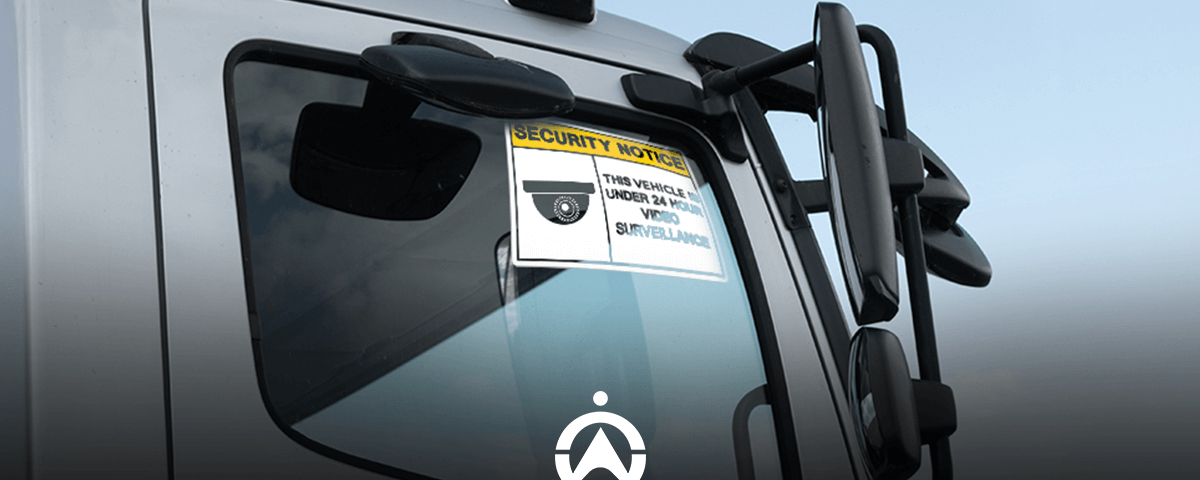 A close-up of a truck’s side mirror displaying a security notice about 24-hour video surveillance.