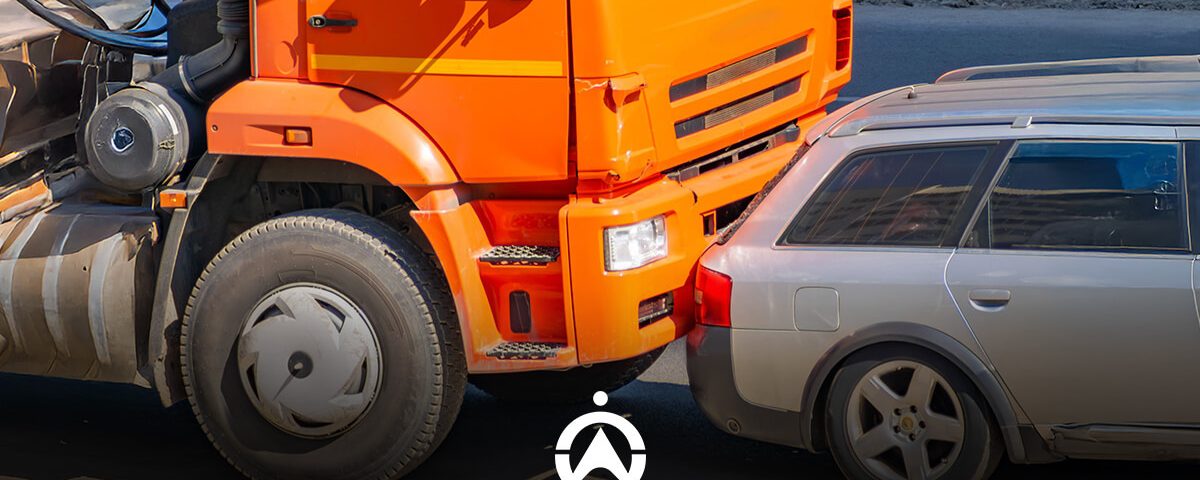 A front view of a collision between an orange truck and a silver car, highlighting damage to both vehicles on a road.