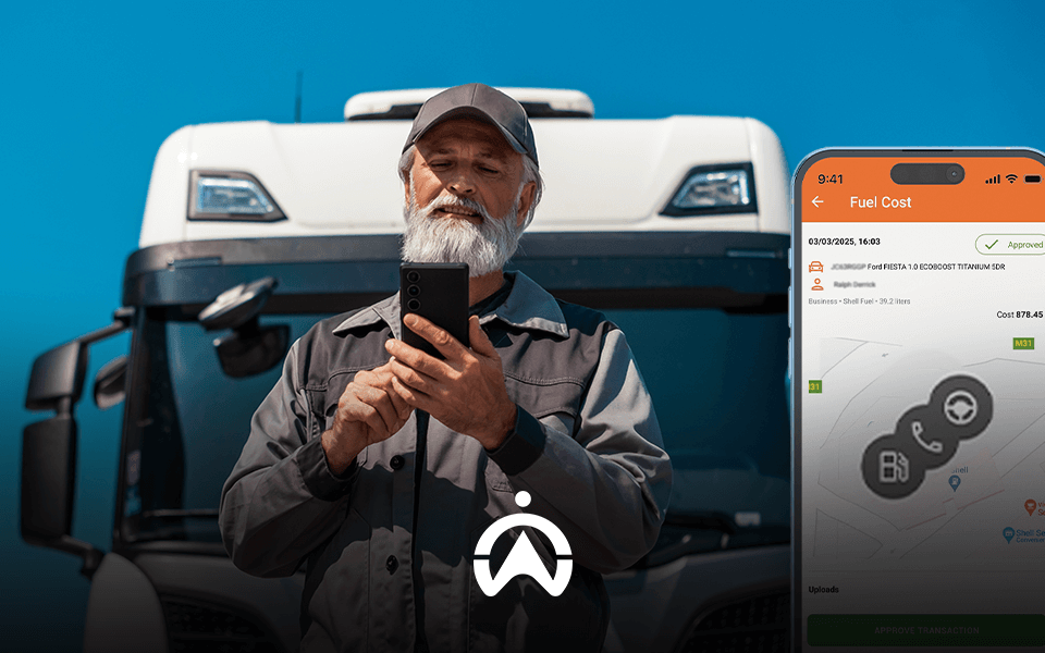 A man in work attire stands in front of a large truck, holding a smartphone displaying fuel cost details, set against a blue sky.