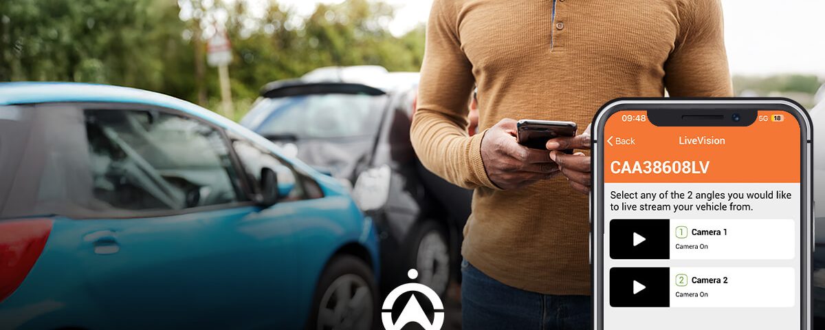 A man holds a smartphone displaying a vehicle livestreaming feature, with parked cars in the background.
