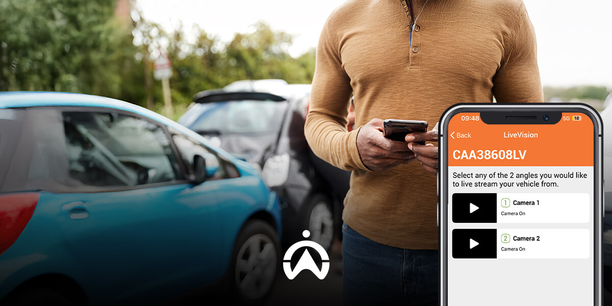 A man holds a smartphone displaying a vehicle livestreaming feature, with parked cars in the background.