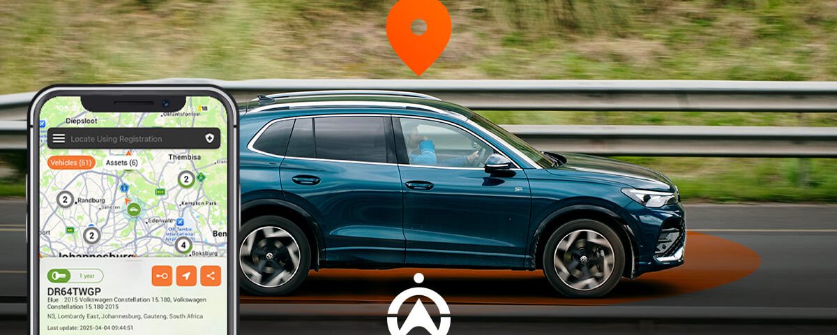 A blue Volkswagen SUV drives past a highway railing, with a smartphone displaying a vehicle tracking map and location pin.