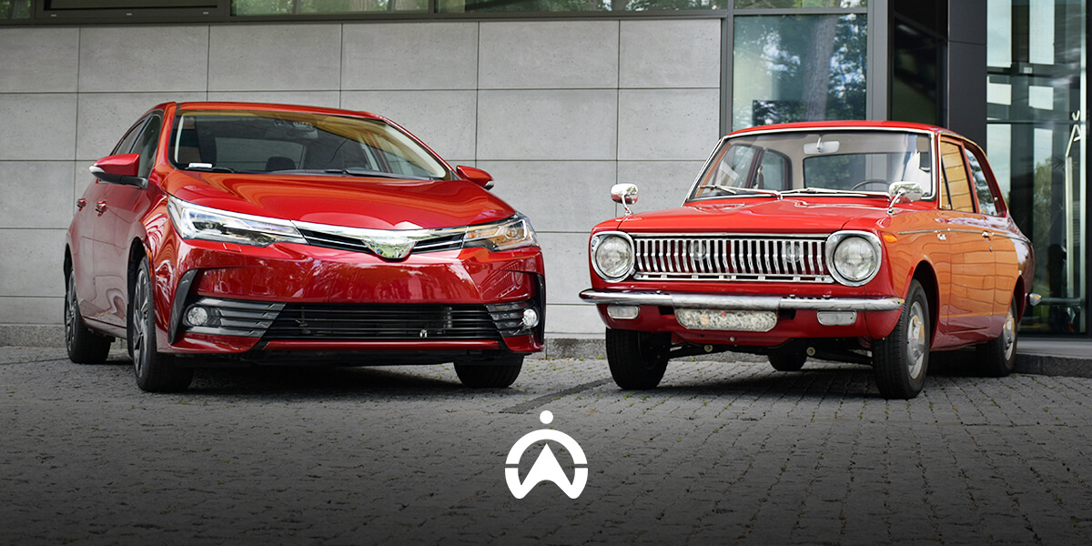 A modern red sedan and a classic red car are parked side by side, showcasing the evolution of automotive design.