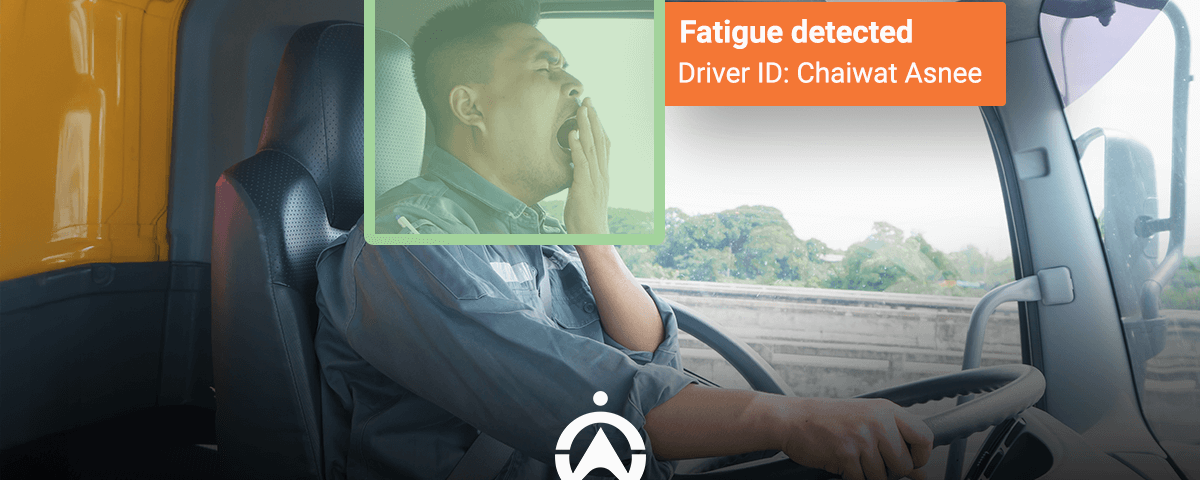 A truck driver sits in the cabin, with alert signs indicating detected fatigue, emphasizing safety on the road.
