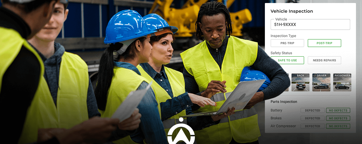 A group of safety-vested individuals conduct a vehicle inspection, reviewing data on a laptop while discussing safety statuses.