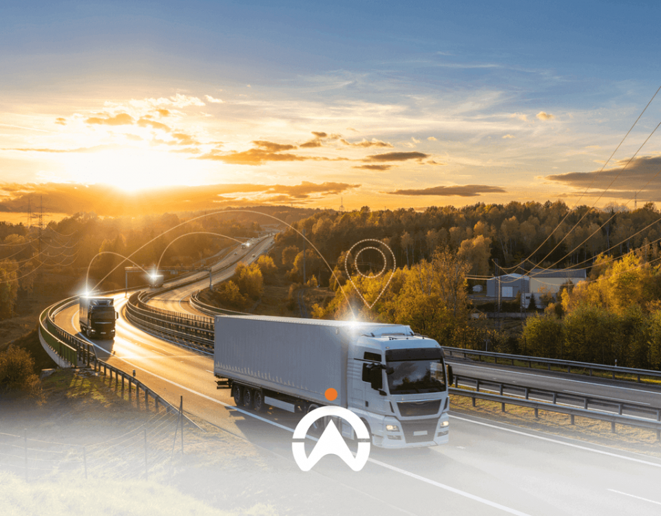 Two trucks drive along a winding road at sunset, surrounded by trees and power lines, symbolizing transport and connectivity.