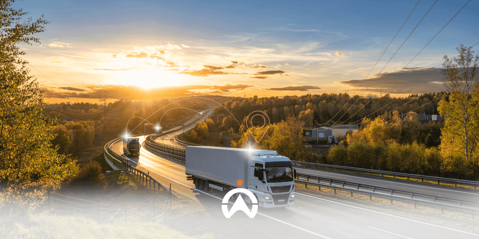 Two trucks drive along a winding road at sunset, surrounded by trees and power lines, symbolizing transport and connectivity.
